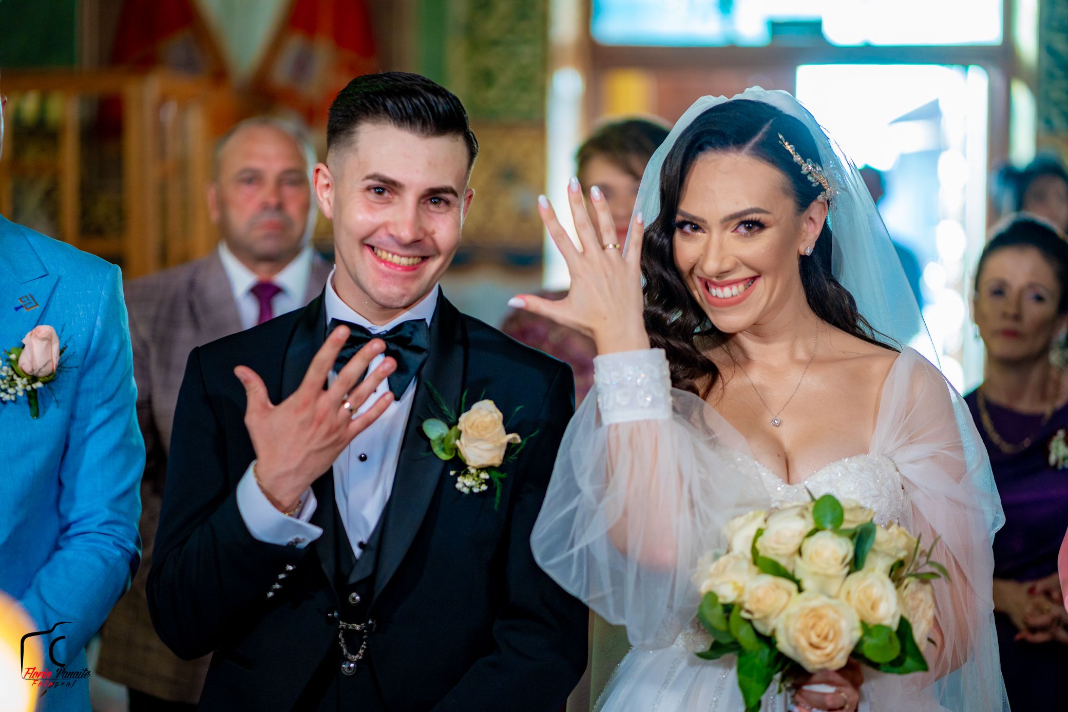 Newlyweds share excited expressions while showing their rings during wedding ceremony.