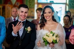 Happy couple displays wedding rings with matching excited expressions during ceremony.