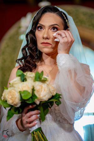 Bride holds cream roses while wearing traditional white veil and gown.
