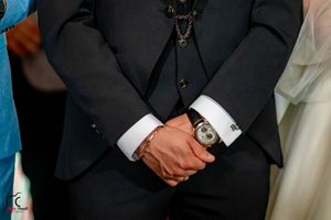 Groomsmen in classic black tuxedos stand in a row at a formal wedding ceremony.