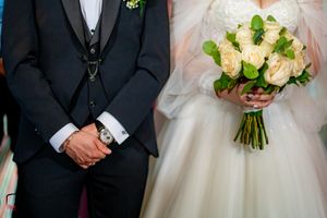 Wedding party members stand together with bride holding classic white rose bouquet.