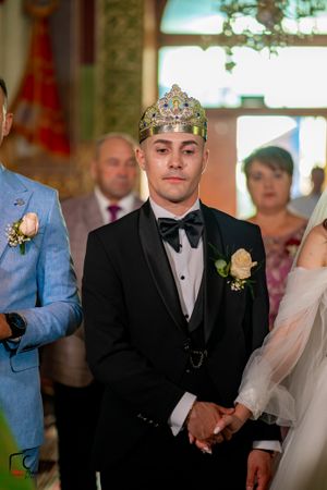 Wedding ceremony in progress with attendees in formal attire and traditional decorations.