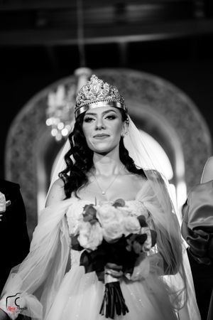 Black and white wedding photo capturing a bride with crown and veil holding a floral bouquet.