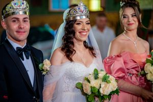 Wedding party members in formal attire with decorative crowns and cream-colored roses.