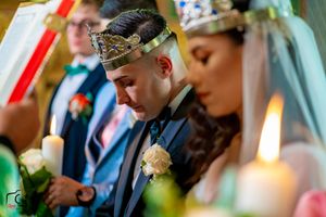 Wedding ceremony participants holding lit candles in an intimate indoor setting.