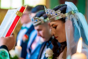 Side profile of wedding ceremony with decorative crowns and candles in green-tinted lighting.