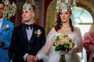 Wedding ceremony participants in formal attire with decorative crowns in an ornate church setting.
