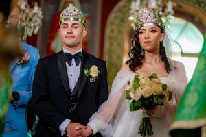 Orthodox wedding ceremony with participants wearing ceremonial crowns in church interior.