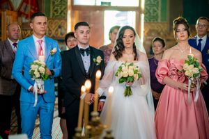 Wedding party and guests gathered in ornate church interior during ceremony.