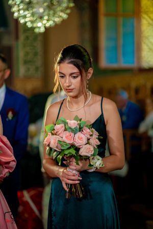 Bridesmaids in navy blue dresses hold pink rose bouquets during a wedding ceremony.