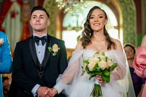 Wedding party members hold bouquets while standing in an ornately decorated venue.