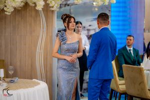 Elegant couple in blue suit and silver dress converse during wedding reception.