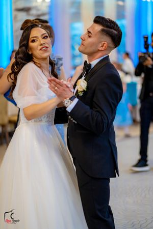 Couple shares joyful moment while dancing at wedding reception with blue lighting.
