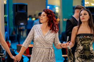 Women in elegant evening gowns dancing at formal celebration with ambient lighting.