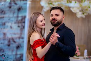Couples dancing in formal attire at an indoor celebration with decorative lighting.