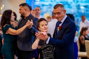 Couples dancing together at an elegant wedding reception with blue ambient lighting.