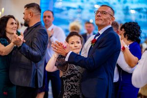 Guests enjoying dancing at a formal event with decorative blue lighting and stone wall details.
