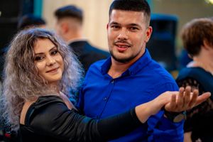 Couples enjoying social dancing at an evening event with blue and black attire.