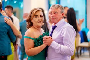 Couples dancing in formal attire at an elegant event with turquoise lighting.