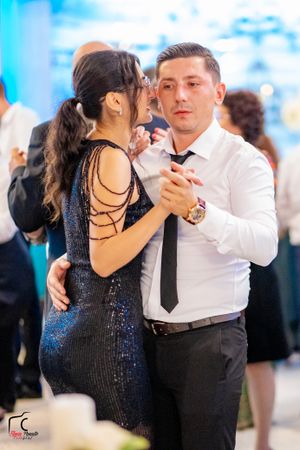 Dancers in formal wear move gracefully across a dance floor with sparkling decor.