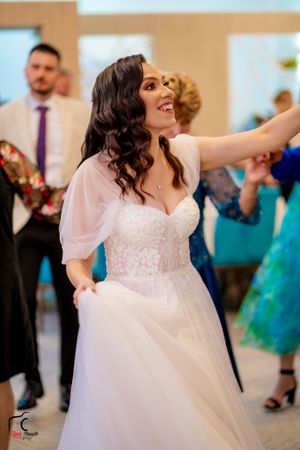 Bride in a flowing white dress with flutter sleeves twirls gracefully on the dance floor at a wedding reception.