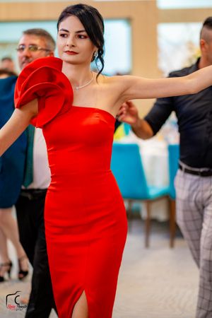 Woman in a striking red formal dress dances elegantly at an event.