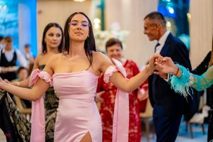 Dancers in pastel pink dresses move gracefully during a formal celebration.