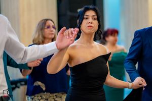 Elegant dancer in a black one-shoulder dress performs gracefully at a formal event.