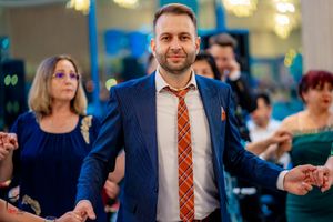 Dancer in navy suit and plaid tie moves energetically on the dance floor at an event.