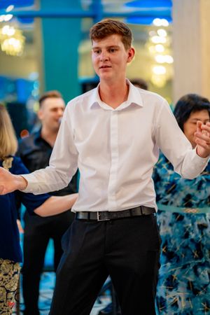 Dancer in crisp white shirt and dark pants performs at an indoor event.
