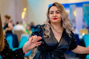 Party guests dancing and celebrating at an elegant event with blue lighting and formal attire.