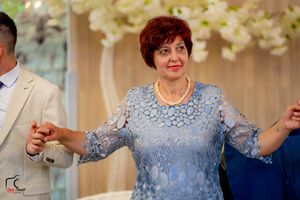 Wedding guests in formal attire dance and celebrate during an elegant reception with floral decorations.