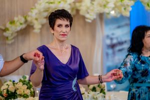 Guests in purple and blue formal attire dance at a wedding reception with elegant decor.