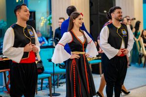Wedding celebration with guests in traditional costumes dancing at an indoor venue.