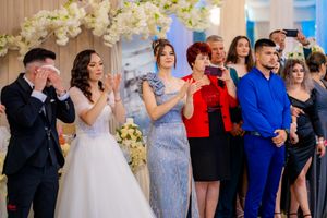 Wedding celebration showing guests in formal wear dancing beneath white floral decorations.