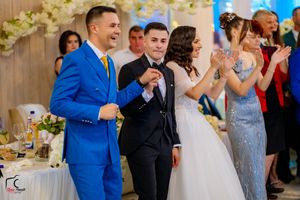 Guests dancing and celebrating at a formal wedding reception with elegant floral arrangements.