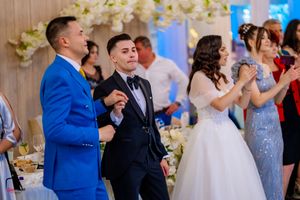 Wedding reception guests in formal attire dancing and celebrating at an elegantly decorated venue.