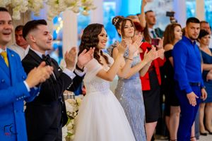 Wedding celebration with guests dancing and clapping in a decorated reception hall.