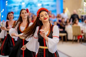 Traditional folk dancers performing in red and white costumes at a wedding celebration.