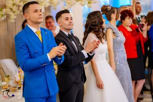 Wedding guests in formal attire applauding during a reception celebration.