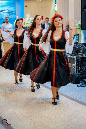 Traditional dancers perform in matching black and white folk costumes with red trim during a cultural celebration.