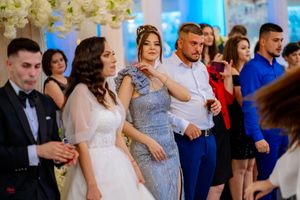 Wedding guests dancing and celebrating at an elegant reception with floral decorations.