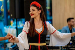 Dancer in traditional folk costume with red headpiece performs at cultural celebration.