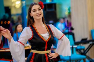 Dancer in traditional folk dress with white sleeves and black bodice performs at celebration.