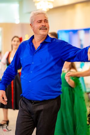 Dancer in bright blue shirt performs with enthusiasm at cultural celebration.