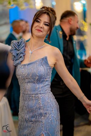 A guest in a sparkling blue formal gown dances gracefully at an elegant event.