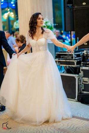 A bride in a flowing white ballgown twirls on the dance floor during a wedding reception.