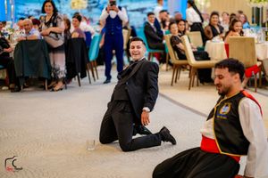 Wedding guests dancing and celebrating at an elegant reception with blue lighting and floral decorations.