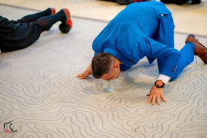 Dancers performing breakdance moves on a light colored floor at a formal event.