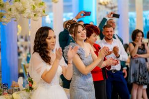 Wedding celebration with guests dancing and enjoying themselves under decorative floral arrangements.